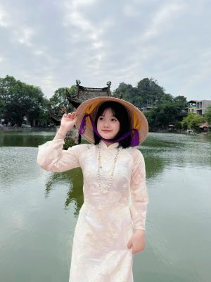 Áo dài cưới là trang phục không thể thiếu trong ngày trọng đại của phụ nữ Việt Nam. Tuy nhiên, cùng với sự phát triển của thời trang, chiếc áo dài cưới truyền thống đã được nâng tầm thành phiên bản áo dài cưới cách tân – một lựa chọn hoàn hảo cho những cô dâu yêu thích sự tinh tế, độc đáo nhưng vẫn giữ trọn vẹn nét duyên dáng, thanh lịch. Áo dài cách tân không chỉ mang lại sự thoải mái, tiện lợi mà còn là tuyên ngôn thời trang mạnh mẽ, giúp cô dâu tỏa sáng rạng rỡ nhất trong hôn lễ.Vì Sao Áo Dài Cưới Cách Tân Lên Ngôi?
Sự nổi lên của áo dài cách tân không phải là ngẫu nhiên. Nó đáp ứng hoàn hảo nhu cầu của cô dâu hiện đại, người mong muốn một trang phục cưới linh hoạt hơn mà vẫn giữ được giá trị văn hóa.1. Thoải Mái và Tiện Lợi:Điểm cộng lớn nhất của áo dài cách tân là sự thoải mái. Thay vì cổ cao truyền thống, áo dài cách tân thường sử dụng các kiểu cổ đa dạng như cổ thuyền, cổ tròn, cổ V hay thậm chí là cổ yếm, giúp cô dâu dễ thở và khoe khéo xương quai xanh quyến rũ. Phần tay áo cũng được biến tấu thành tay lỡ, tay phồng hoặc tay bồng, tạo sự trẻ trung và năng động, thuận tiện hơn cho việc di chuyển, đón khách trong suốt buổi tiệc.2. Đa Dạng Trong Thiết Kế và Chất Liệu:Nếu áo dài truyền thống bị giới hạn về chất liệu và phom dáng, áo dài cách tân mở ra cánh cửa sáng tạo vô tận. Cô dâu có thể lựa chọn các loại vải hiện đại hơn như Voan, Organza, Taffeta, kết hợp với các kỹ thuật thủ công tinh xảo như đính kết 3D, thêu chỉ ánh kim, hay sử dụng kỹ thuật cắt may hiện đại để tạo ra các chi tiết xếp ly, nhún bèo độc đáo ở vai, eo hoặc tà áo.3. Phù Hợp Với Mọi Vóc Dáng và Địa Điểm Cưới:Nhờ sự linh hoạt trong thiết kế, áo dài cách tân có thể "chiều lòng" mọi vóc dáng. Tà áo được biến tấu thành tà ngắn ngang gối, tà lửng, hoặc tà kép với độ bồng bềnh nhẹ, giúp cô dâu có chiều cao khiêm tốn trông thanh thoát hơn, đồng thời phù hợp với cả tiệc cưới ngoài trời, bãi biển hay không gian nhà hàng sang trọng.Những Xu Hướng Áo Dài Cưới Cách Tân Đang Được Yêu Thích
Thị trường áo dài cưới cách tân luôn sôi động với những ý tưởng mới mẻ. Dưới đây là ba xu hướng nổi bật nhất mà cô dâu không thể bỏ qua:1. Áo Dài Tà Kép và Tay Bồng (Tà Phồng):Đây là sự kết hợp hoàn hảo giữa nét kiêu sa của váy cưới phương Tây và sự dịu dàng của áo dài Việt Nam. Tà áo dài được may hai lớp, lớp trong bằng lụa mỏng ôm sát, lớp ngoài bằng Voan hoặc Organza tạo độ phồng nhẹ. Tay bồng hoặc tay phồng nhẹ nhàng ở vai giúp cô dâu có bờ vai thon gọn và tăng thêm vẻ lãng mạn, cổ tích.2. Áo Dài Kết Hợp Họa Tiết Hiện Đại và Màu Sắc Táo Bạo:Không chỉ giới hạn ở các màu đỏ, trắng, vàng truyền thống, áo dài cách tân hiện đại còn sử dụng các tông màu pastel (xanh ngọc, hồng đất) hoặc màu sắc đậm (xanh navy, tím than) để tạo sự khác biệt. Họa tiết được ứng dụng là các mảng thêu, đính kết pha lê theo phong cách tối giản, hoặc hình khối hiện đại thay vì rồng phượng cầu kỳ như trước, tạo cảm giác tinh tế và sang trọng.3. Áo Dài Cổ Yếm/Cổ Thuyền Kết Hợp Quần Culottes/Chân Váy:Đối với cô dâu muốn sự đột phá, áo dài cưới cách tân còn được kết hợp cùng quần Culottes (ống rộng) hoặc chân váy xòe/chân váy chữ A, thay thế cho chiếc quần lụa bó sát truyền thống. Sự kết hợp này mang đến vẻ ngoài cực kỳ thời thượng, tiện dụng như một bộ đầm dạ hội mà vẫn giữ được kiểu dáng thân áo dài duyên dáng. Áo dài cổ yếm hoặc cổ thuyền khoe trọn vẻ đẹp của cổ và vai, đặc biệt phù hợp với cô dâu có phong cách gợi cảm, phóng khoáng.Bí Quyết Lựa Chọn Áo Dài Cưới Cách Tân Chuẩn Nhất Cho Cô Dâu
Để chiếc áo dài cách tân thật sự hoàn hảo, cô dâu cần lưu ý những điểm sau trong quá trình lựa chọn và đặt may:1. Chọn Kiểu Dáng Phù Hợp Với Dáng Người:Dáng người tròn, đầy đặn: Nên chọn áo dài có chất liệu đứng form như Gấm, Taffeta, tránh các chất liệu quá mỏng hoặc bóng. Ưu tiên cổ V hoặc cổ tim để tạo cảm giác thon gọn.Dáng người gầy, cao: Thích hợp với các kiểu áo dài có tà bồng, tay phồng, và có thể chọn chất liệu có độ bóng như Lụa để tạo cảm giác đầy đặn hơn.Dáng người quả lê (hông lớn): Chọn áo dài có tà xòe nhẹ, độ dài tà phủ mắt cá chân để cân đối lại tỷ lệ cơ thể.2. Ưu Tiên Sự Hài Hòa Của Tổng Thể:Dù là cách tân, cô dâu vẫn cần đảm bảo sự hài hòa với trang phục của chú rể và tổng thể phong cách tiệc cưới. Nếu tiệc cưới theo phong cách Vintage, nên chọn áo dài cách tân với màu sắc trầm ấm, họa tiết ren hoặc thêu tay cổ điển. Nếu tiệc cưới hiện đại, hãy mạnh dạn chọn màu sắc tươi sáng và họa tiết 3D nổi bật.3. Chất Lượng Vải và Kỹ Thuật May:Chất liệu là yếu tố quyết định sự sang trọng của chiếc áo dài. Hãy chọn studio, nhà may uy tín, nơi sử dụng chất liệu nhập khẩu, kỹ thuật cắt may chính xác và tay nghề thợ thêu, đính kết cao cấp. Một chiếc áo dài cách tân đẹp không chỉ nằm ở kiểu dáng mà còn ở độ rũ, độ đứng form và sự thoải mái khi mặc.4. Đừng Quên Phụ Kiện Đi Kèm:Phụ kiện đi kèm áo dài cách tân cũng nên được tối giản hóa. Thay vì mấn truyền thống, cô dâu có thể sử dụng cài tóc, vương miện nhỏ hoặc khăn voan ngắn, kết hợp với giày cao gót mũi nhọn đơn giản để tôn lên nét hiện đại, thanh thoát của trang phục.Tương Lai Của Áo Dài Cưới Cách Tân
Áo dài cưới cách tân không chỉ là một xu hướng nhất thời mà còn là minh chứng cho thấy trang phục truyền thống có thể thích nghi và phát triển cùng thời đại. Với sự sáng tạo không ngừng nghỉ của các nhà thiết kế Việt Nam, áo dài cách tân chắc chắn sẽ tiếp tục là nguồn cảm hứng bất tận, mang đến những kiệt tác thời trang cưới độc đáo, giúp mỗi cô dâu Việt Nam tự tin, kiêu hãnh và thật sự lộng lẫy trong ngày hạnh phúc nhất đời mình.Lựa chọn áo dài cưới cách tân là lựa chọn sự giao thoa hoàn hảo giữa quá khứ và hiện tại, tôn vinh vẻ đẹp truyền thống mà không hề lạc hậu, giúp cô dâu tạo nên dấu ấn cá nhân khó quên.